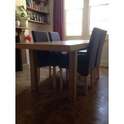 Extendable wooden dining room table in excellent condition with 4 grey material, wooden chairs.