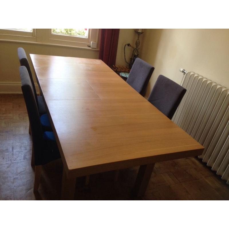 Extendable wooden dining room table in excellent condition with 4 grey material, wooden chairs.